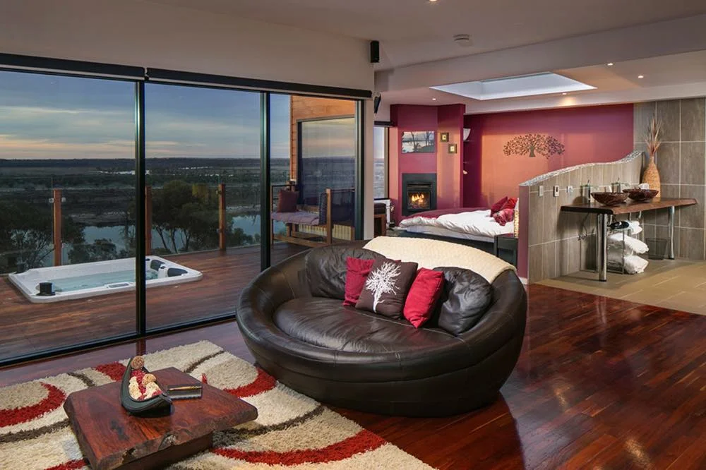 riverland open-plan villa interior with floor-to-ceiling windows, modern kitchen, fireplace and access to outdoor spa area